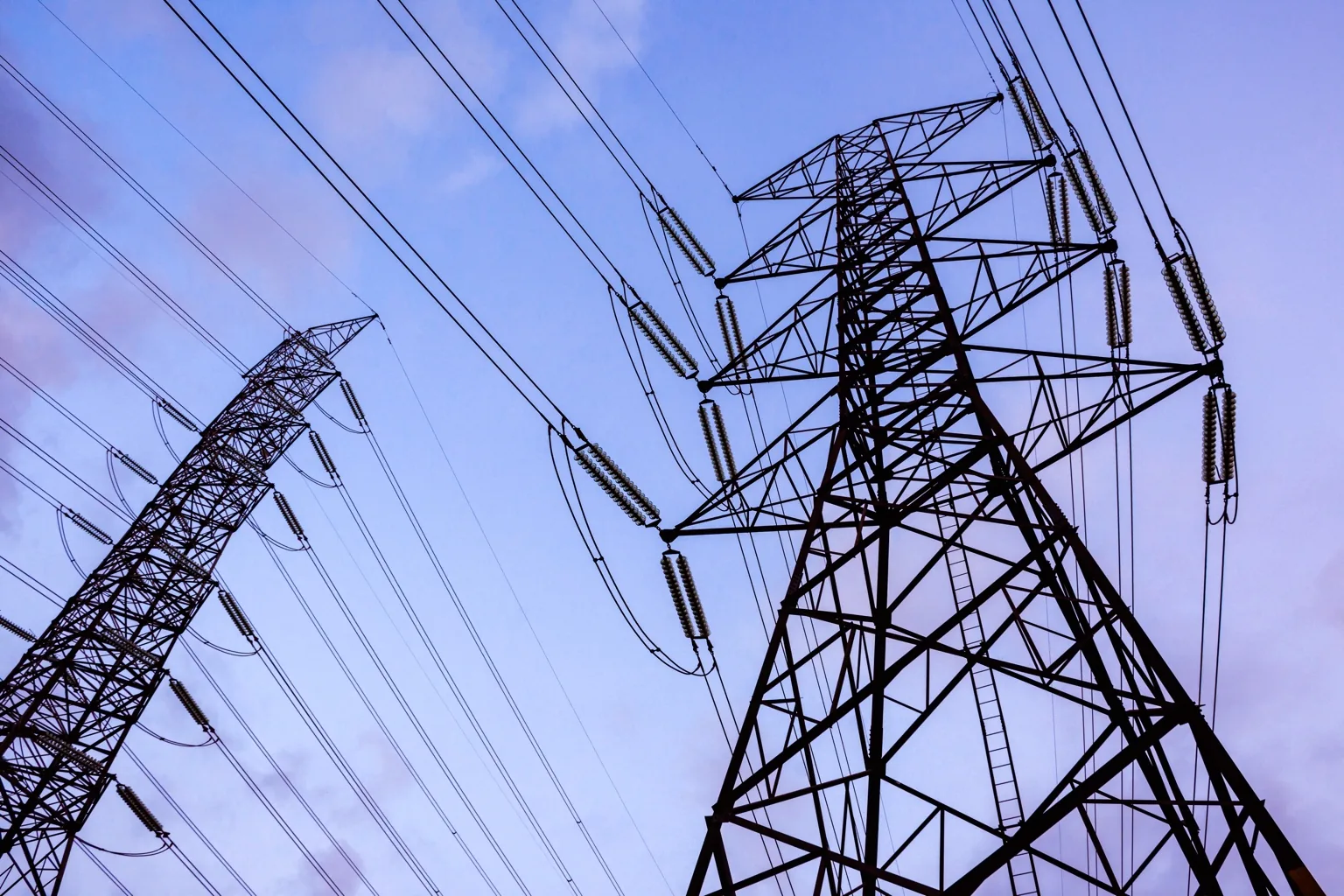 High-voltage electricity transmission towers and power lines against a blue sky.